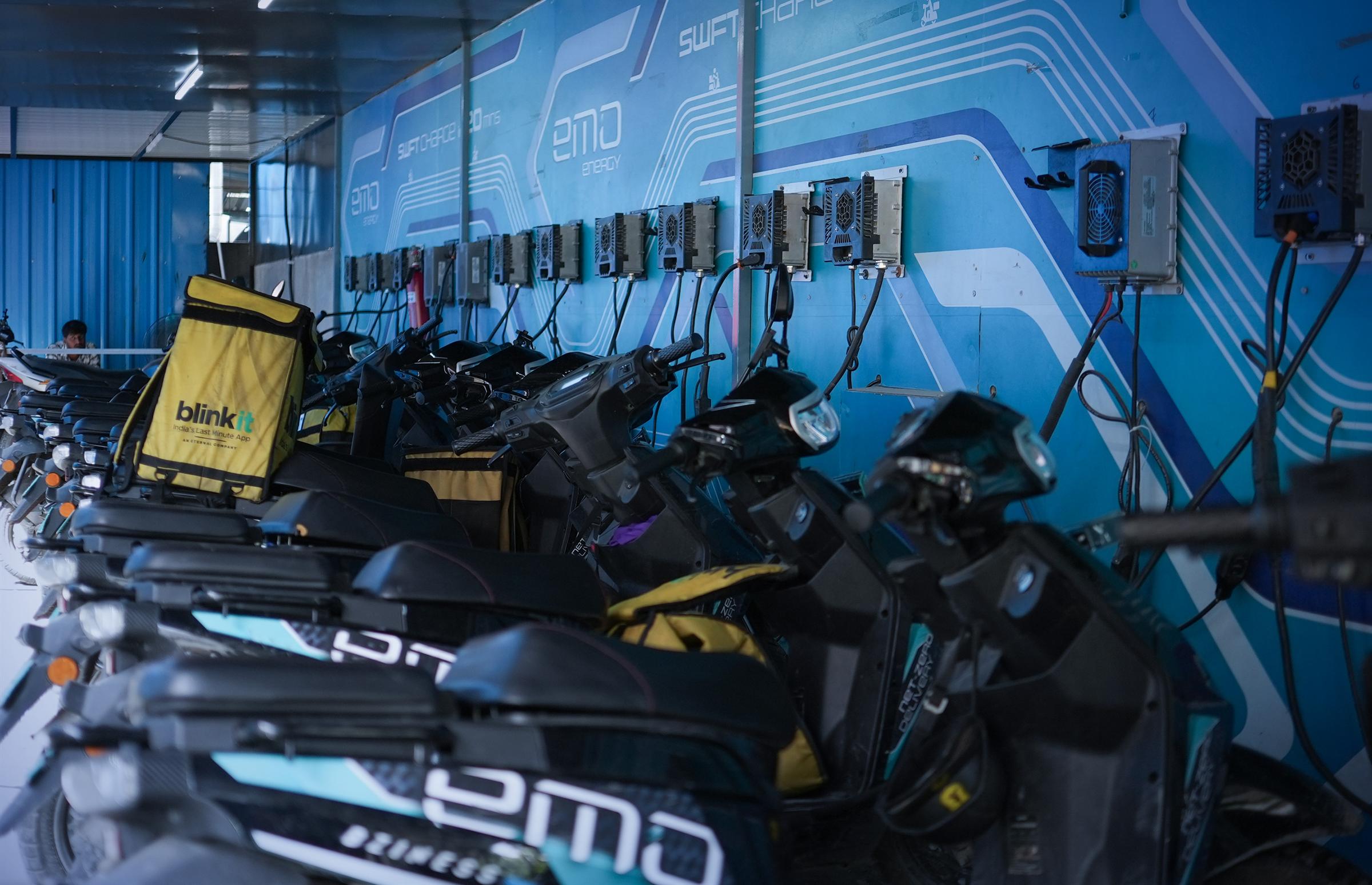 Rows of EMO scooters charging inside an EMO swift-charge station